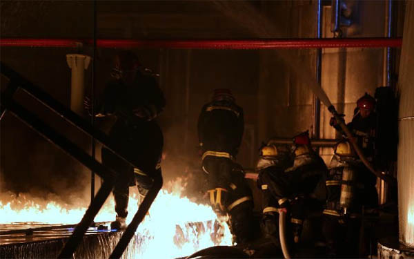 消防救援人員正在近距離對失火的儲罐區處理