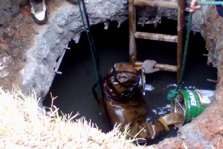 身穿防化服背空氣呼吸器對污水池進行清理